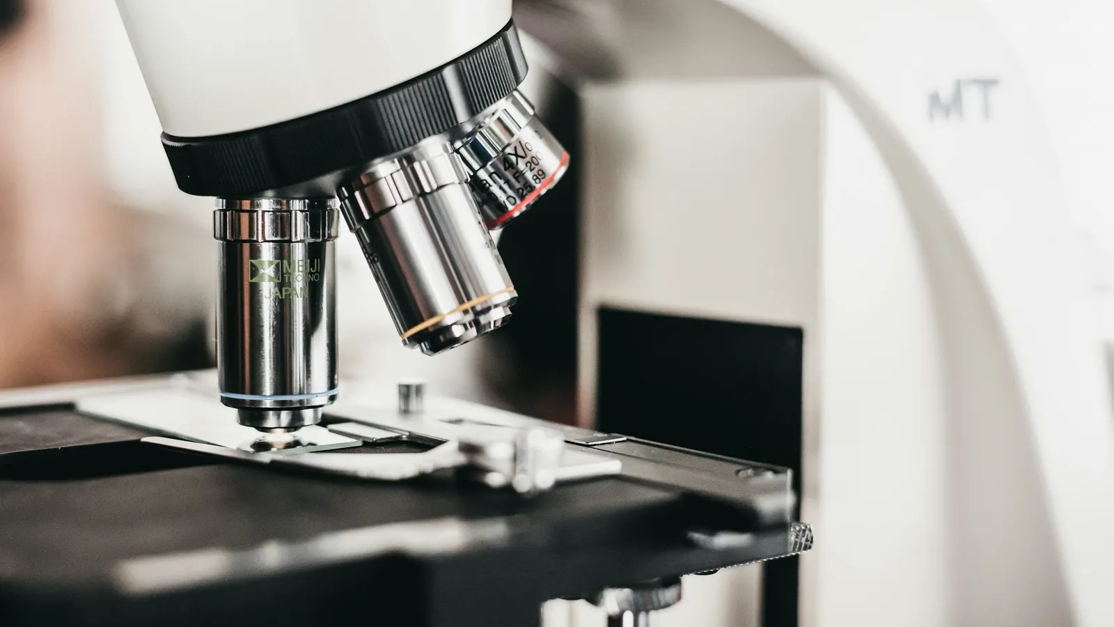 Close-up of a light microscope with objective lenses above the stage