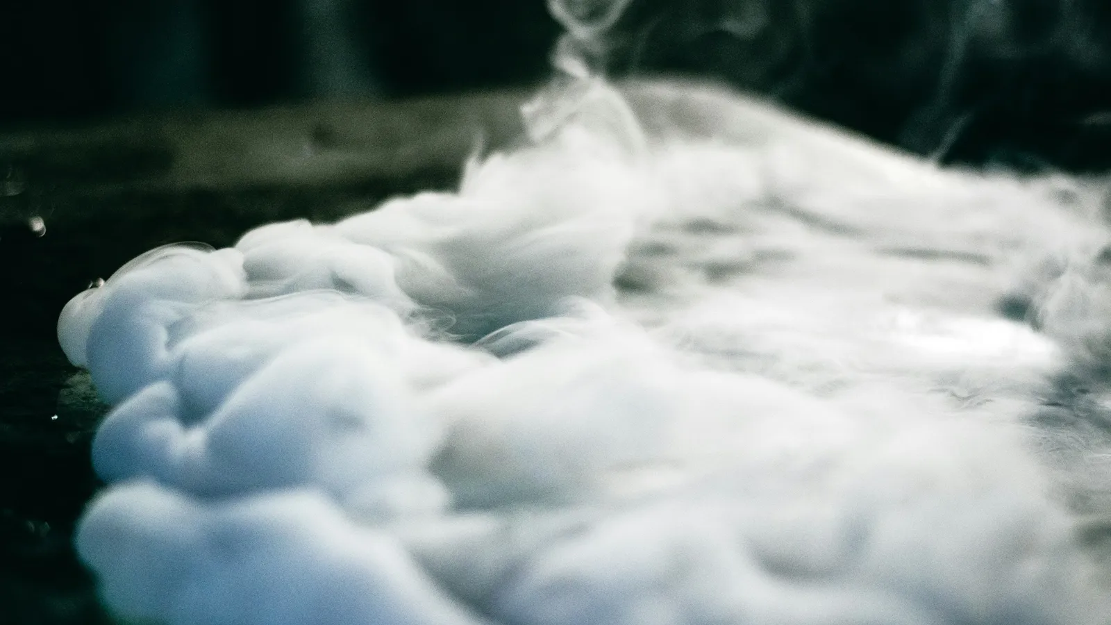 Cold white vapour spilling across a dark surface