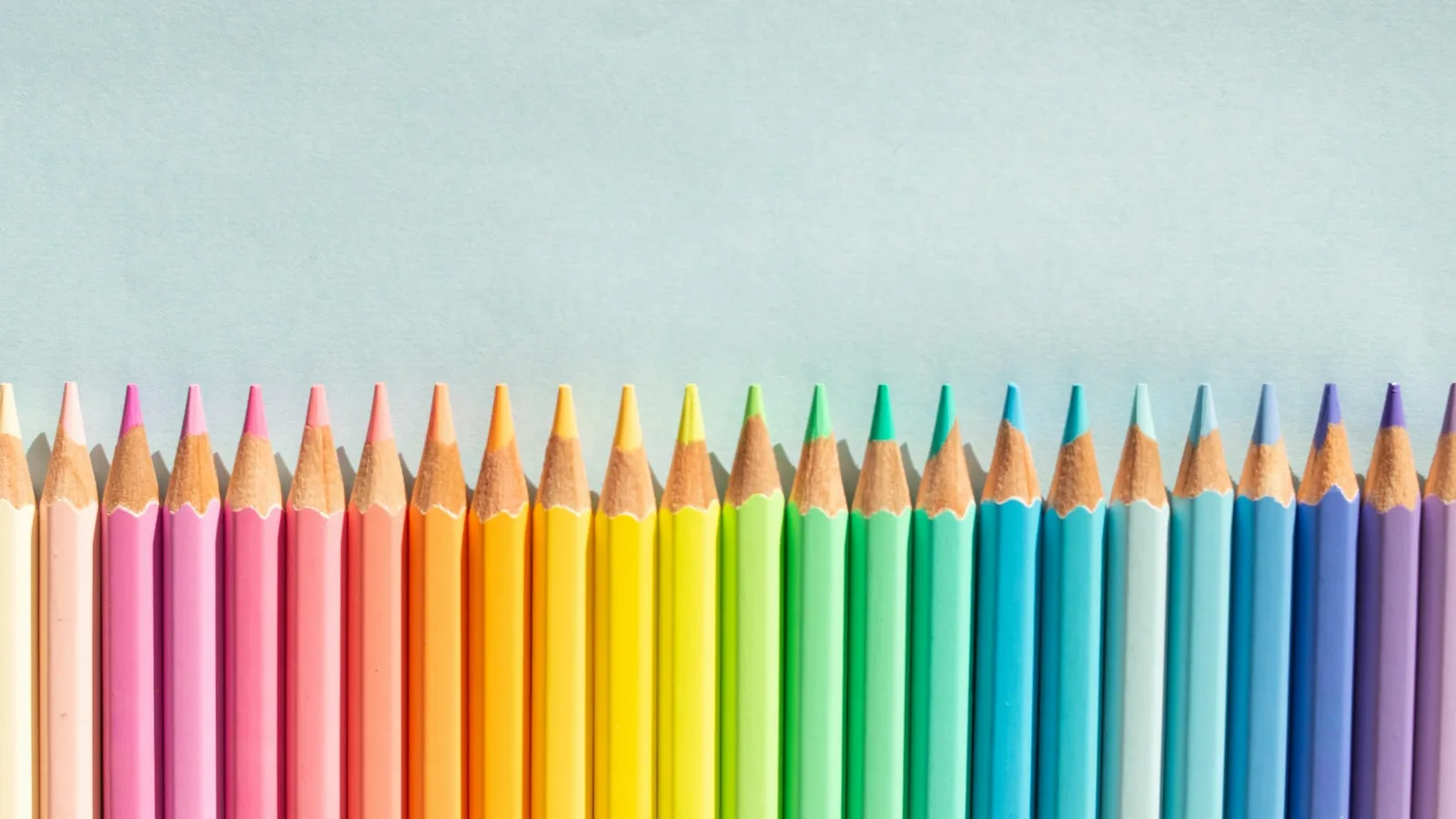 Coloured pencils arranged in a row by colour