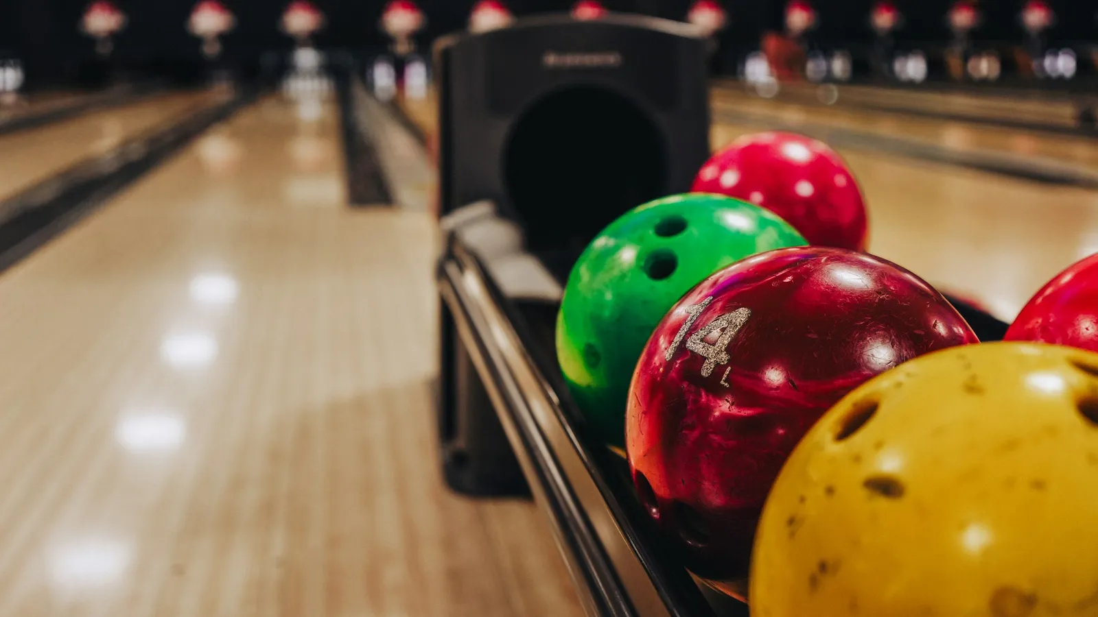 Colourful bowling balls lined up at the end of a lane