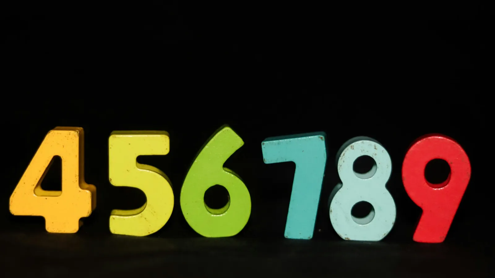 Colourful numbers four to nine on a black background