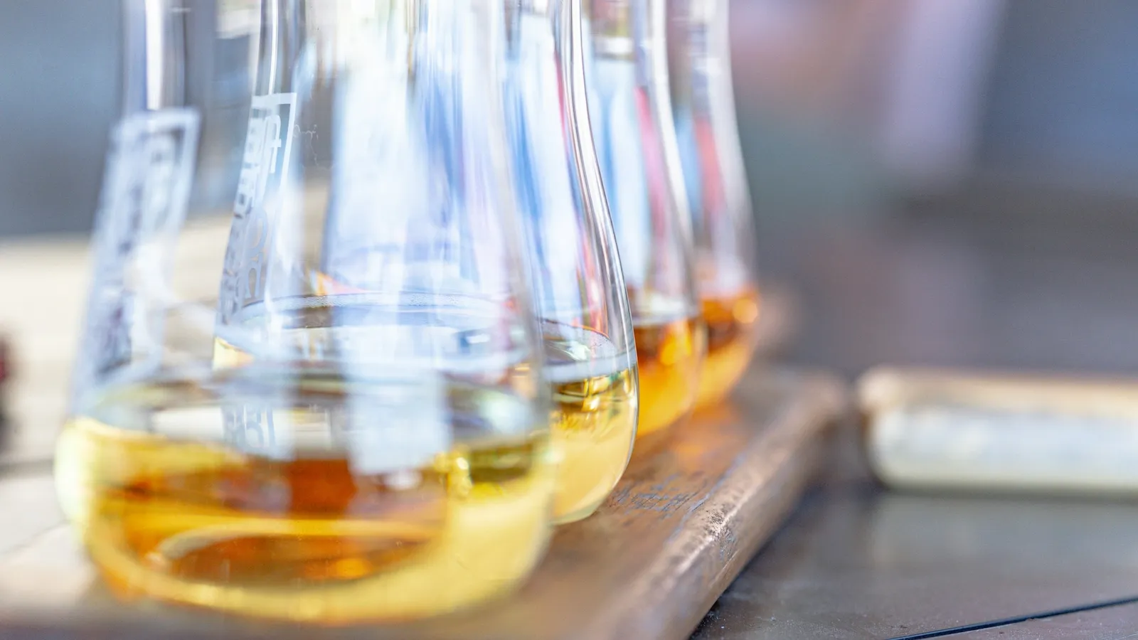Conical flasks of amber liquid on a lab bench