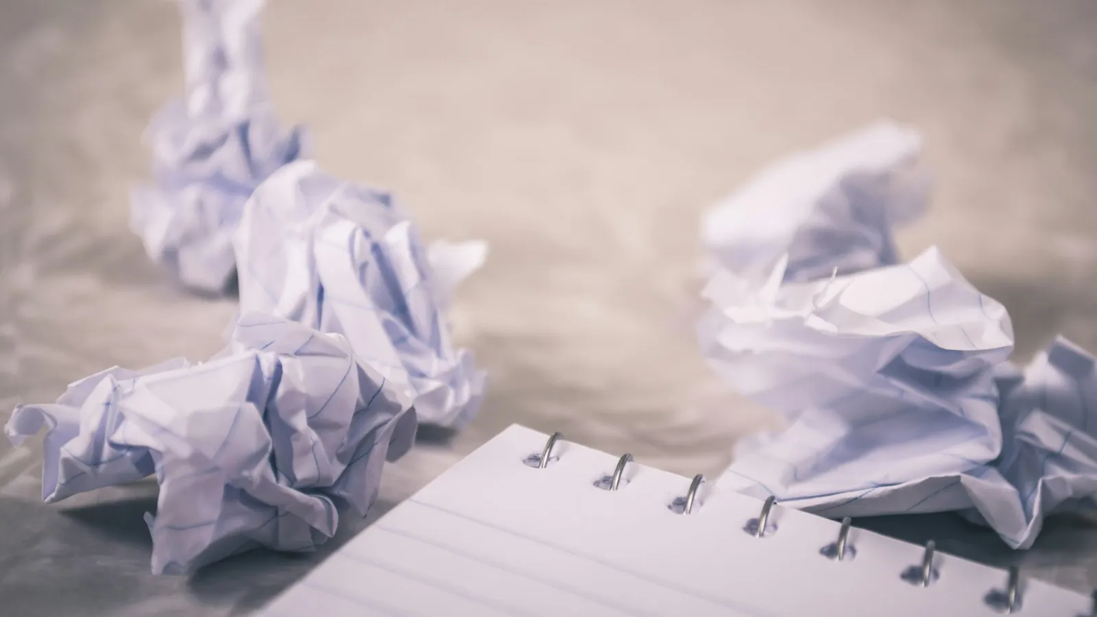Crumpled balls of paper next to an open notebook