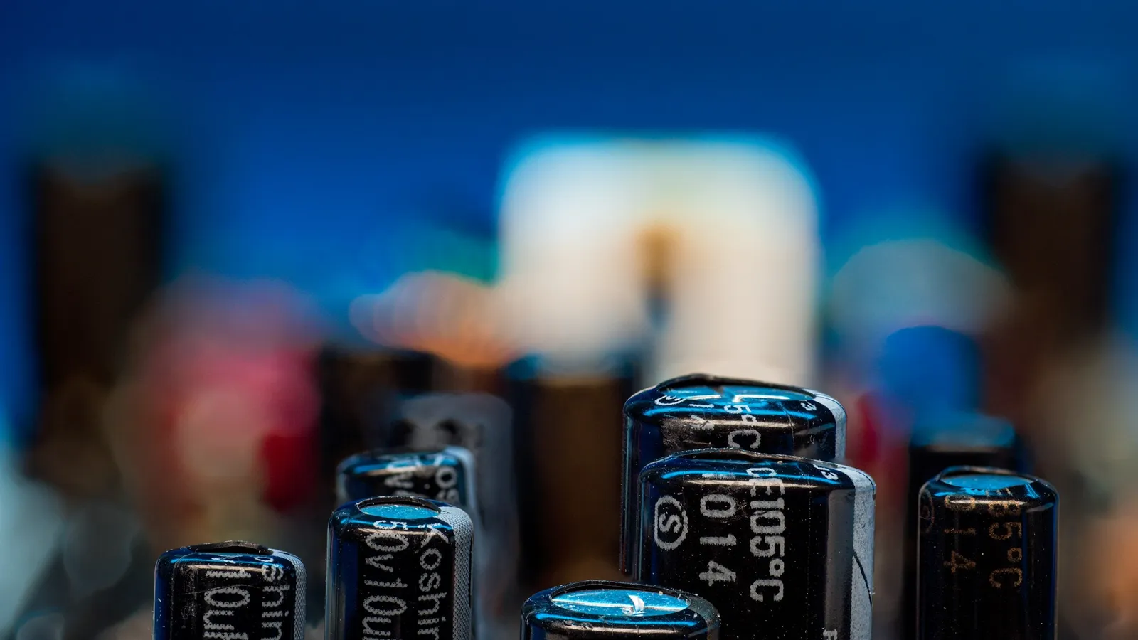 Cylindrical capacitors standing on a circuit board, in soft focus