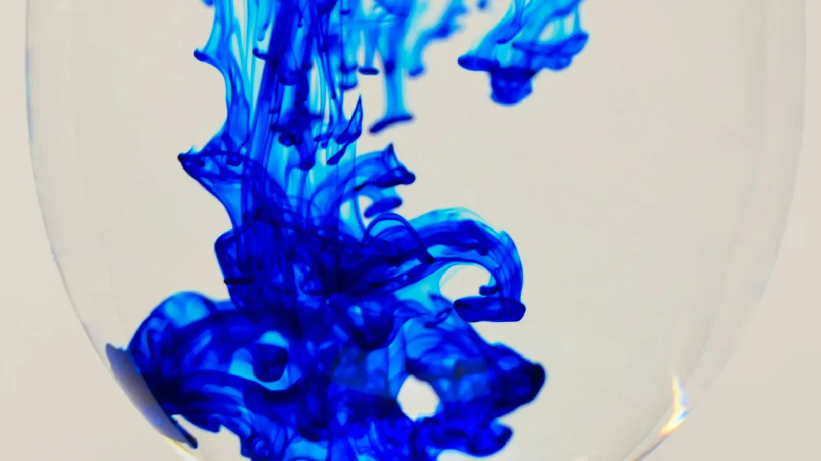 Deep blue colour swirling down through water in a glass