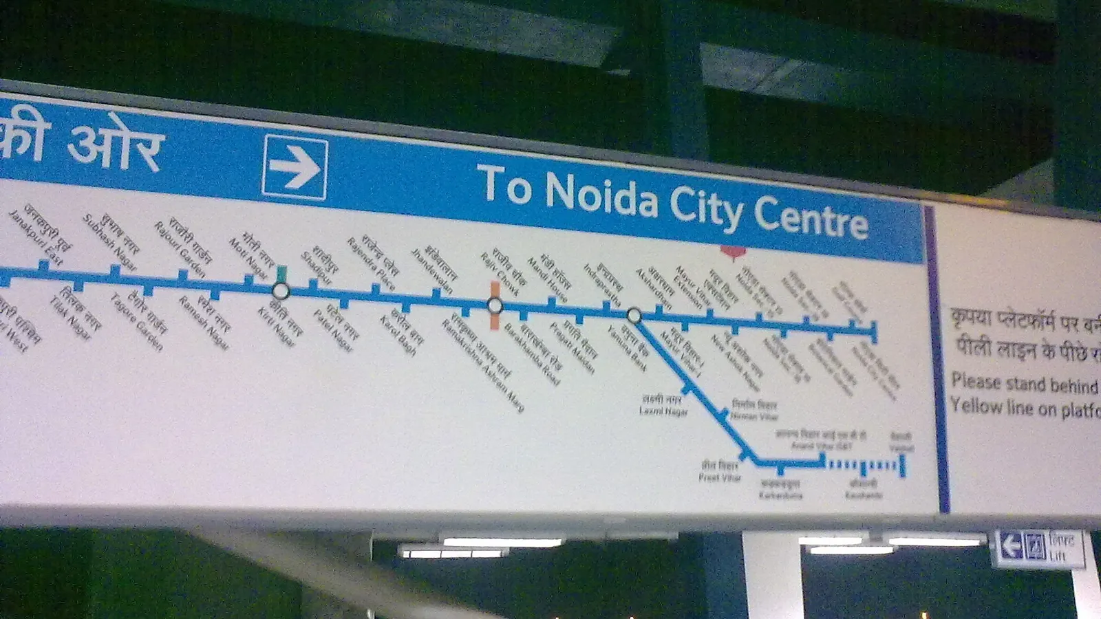 Delhi Metro Blue Line route map sign on a station platform, pointing to Noida City Centre