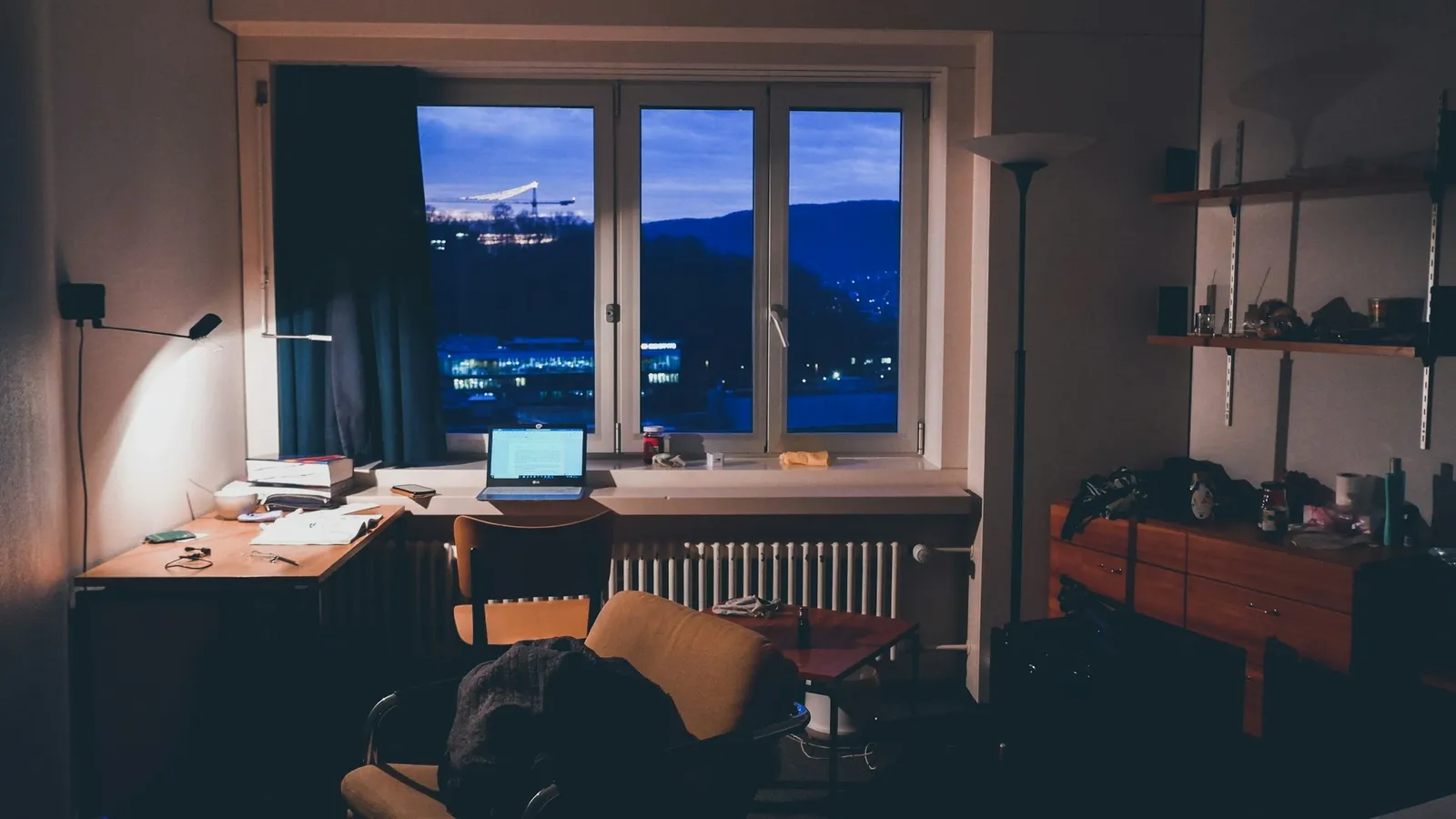 Desk lit by a lamp at night by a window