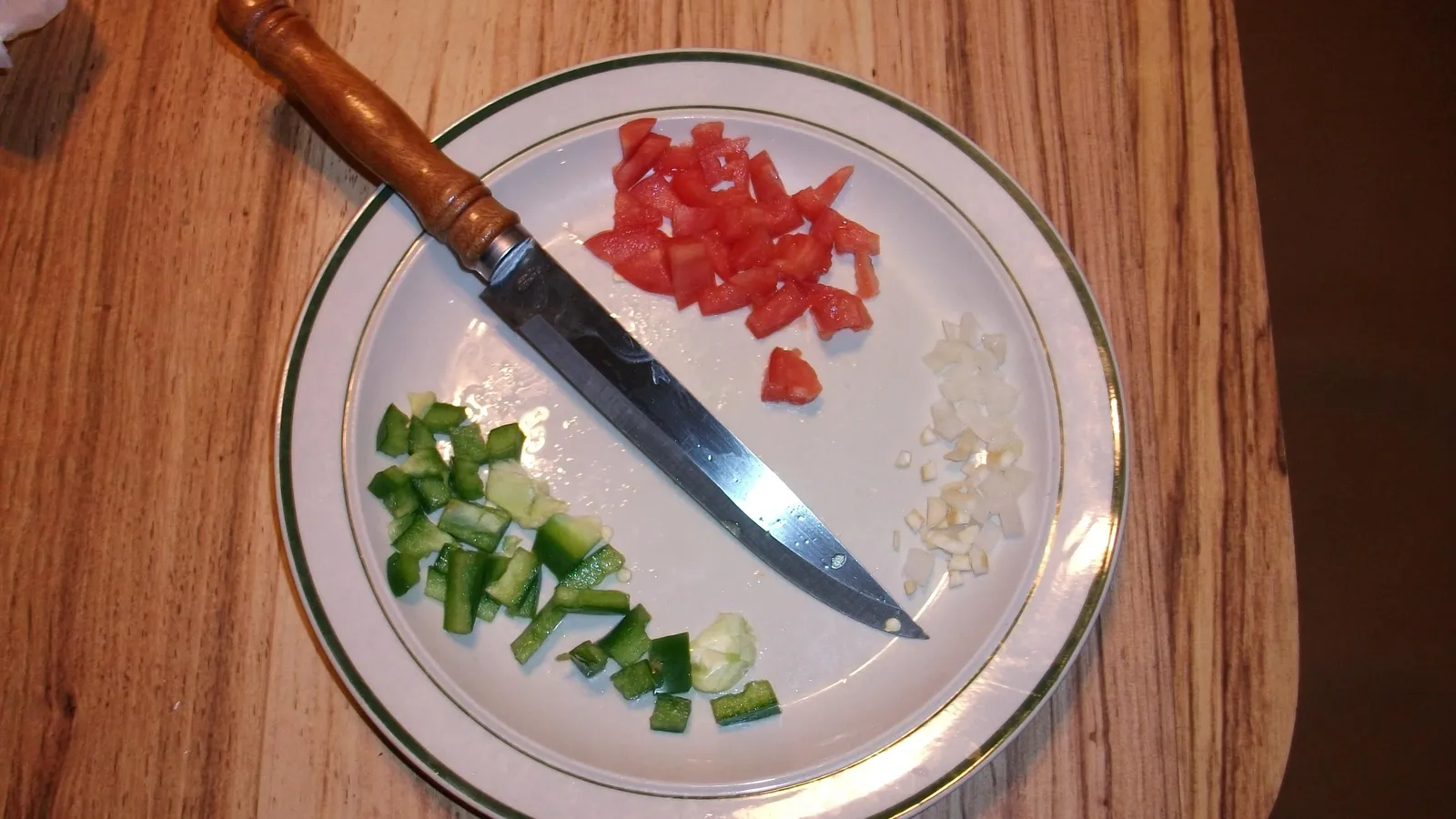 Diced tomato, green capsicum and onion on a white plate with a kitchen knife