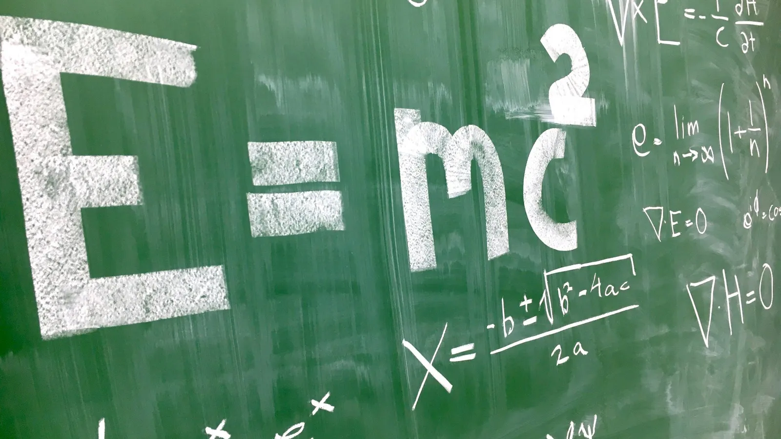 E = mc squared written on a green chalkboard