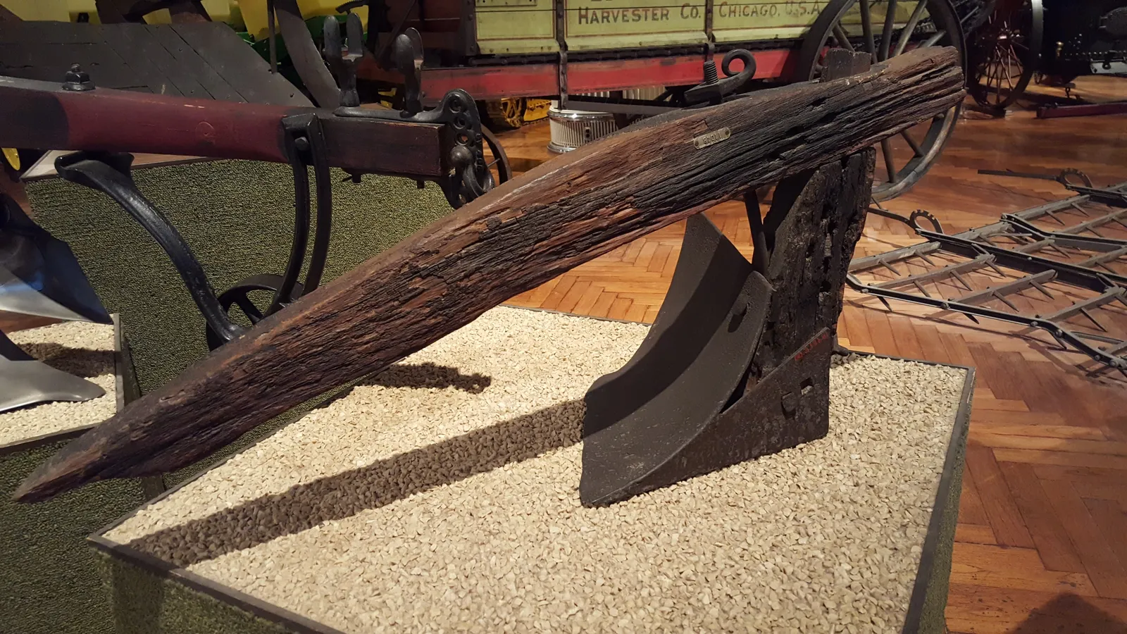Early John Deere plough with curved metal mouldboard and weathered wooden beam in a museum
