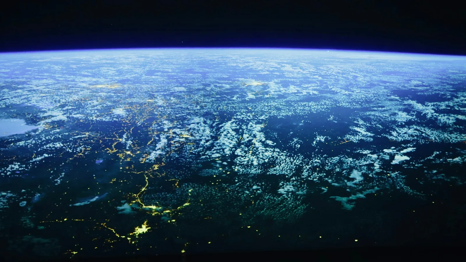 Earth seen from orbit with city lights below