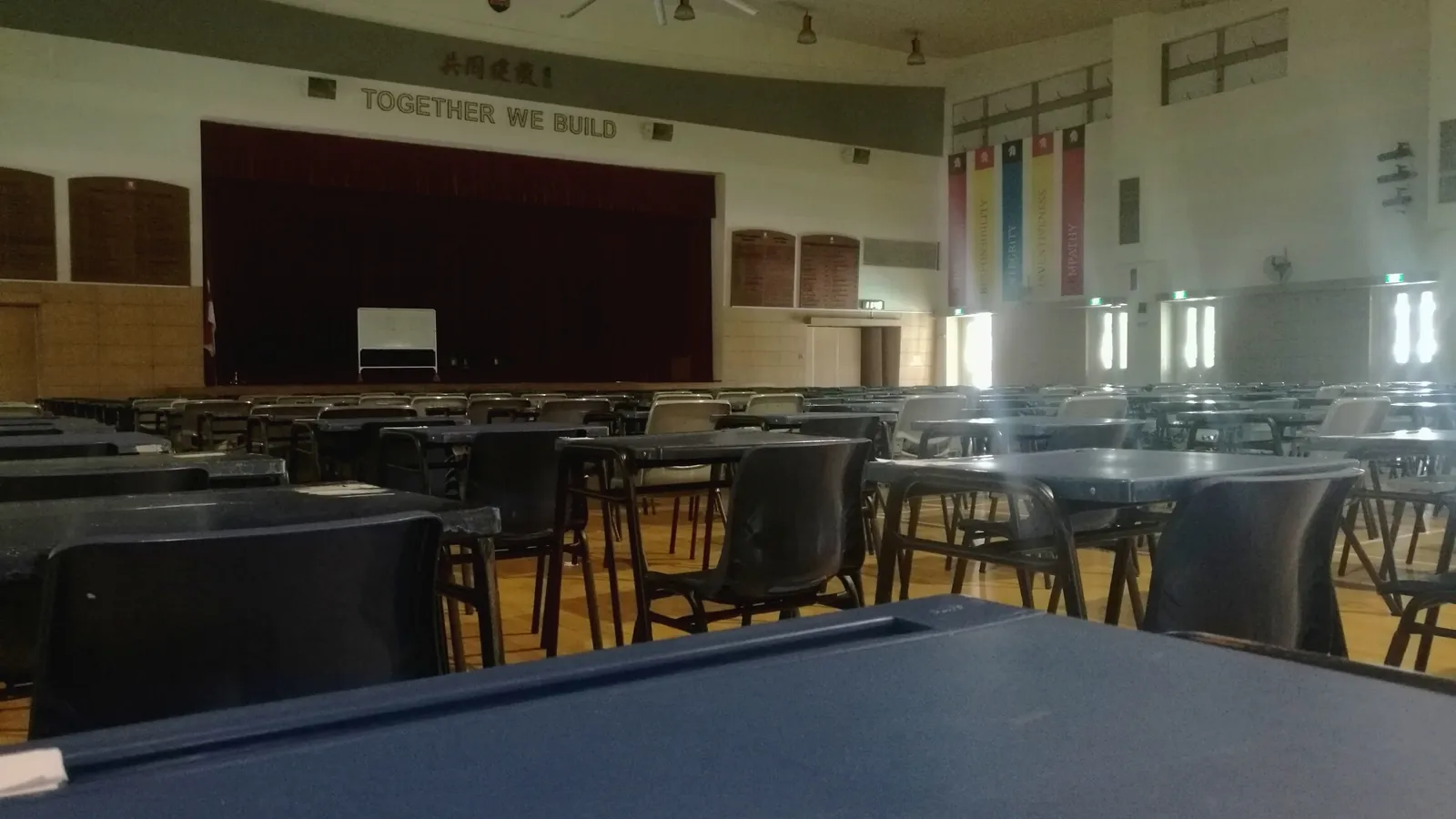 Empty desks set up for an exam in a large college hall