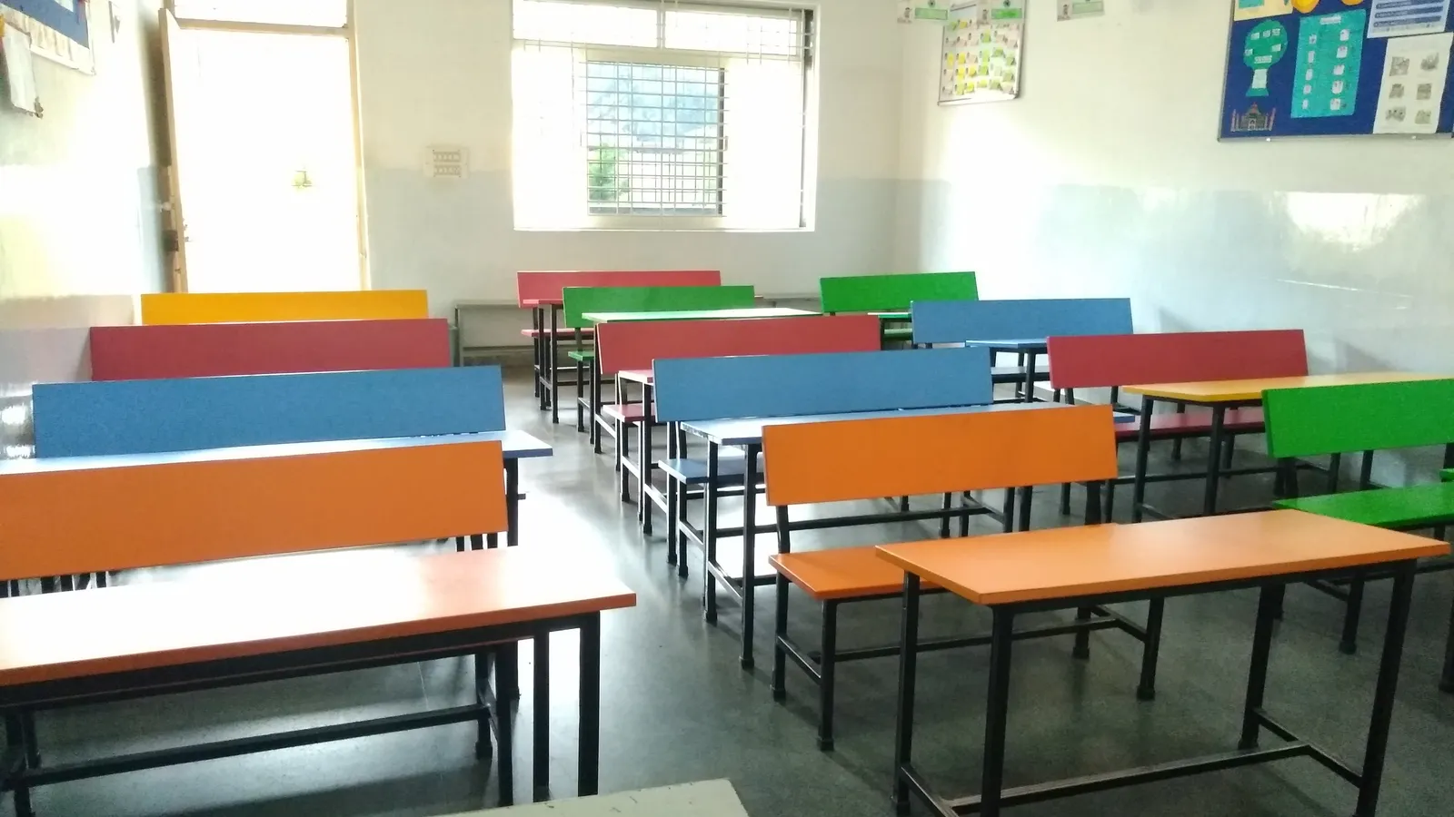 Empty Indian school classroom with rows of brightly coloured benches and desks