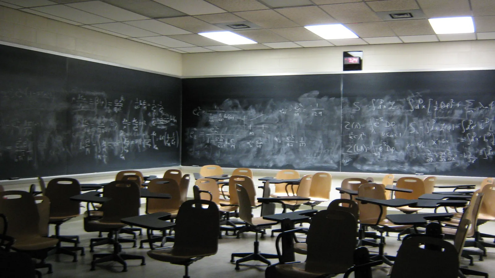 Empty lecture room with chairs and half-erased equations on blackboards