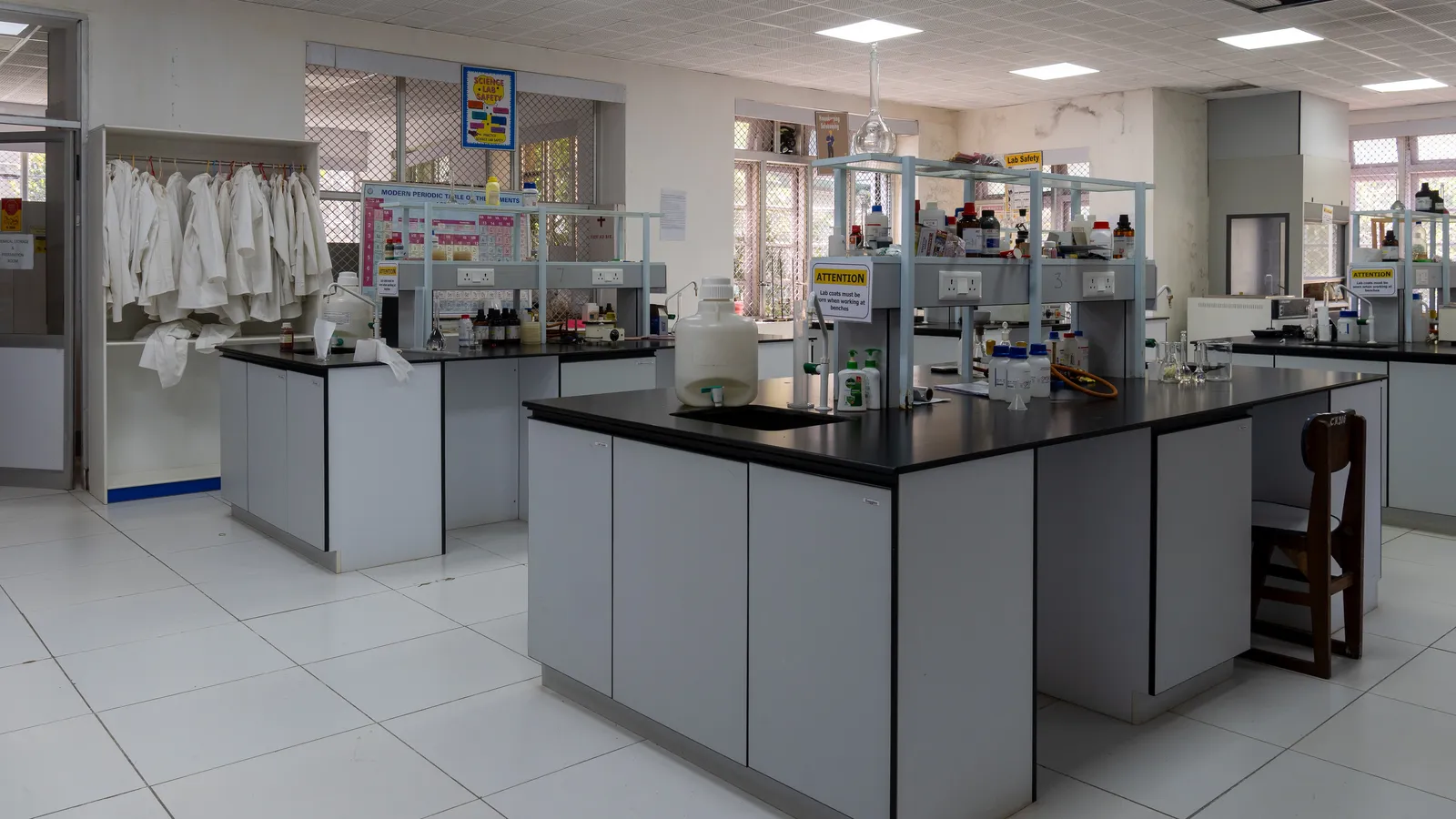 Empty school chemistry lab with benches, reagent shelves and hanging lab coats