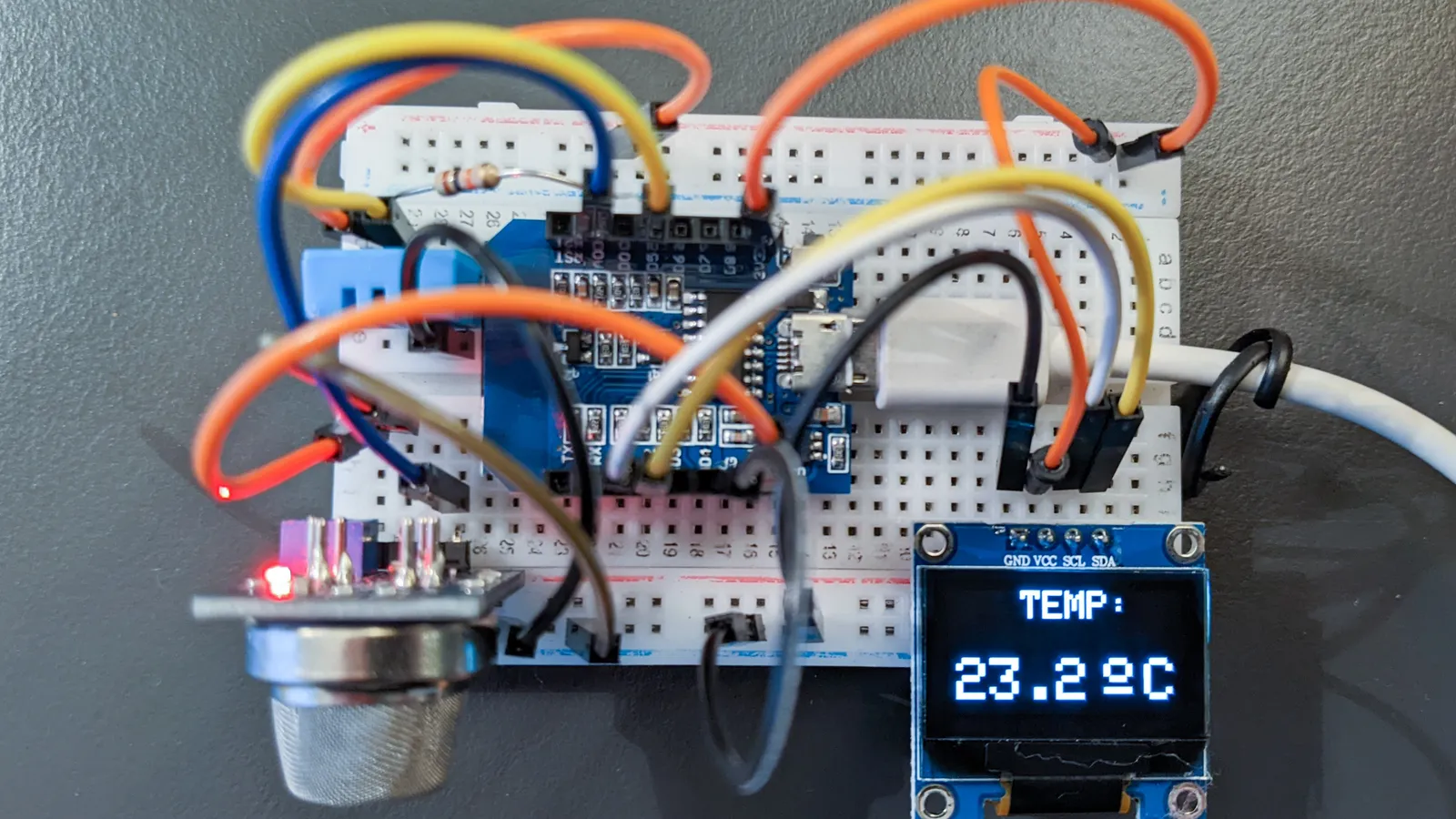 ESP8266 microcontroller board on a breadboard wired to sensors and a display reading 23.2 °C