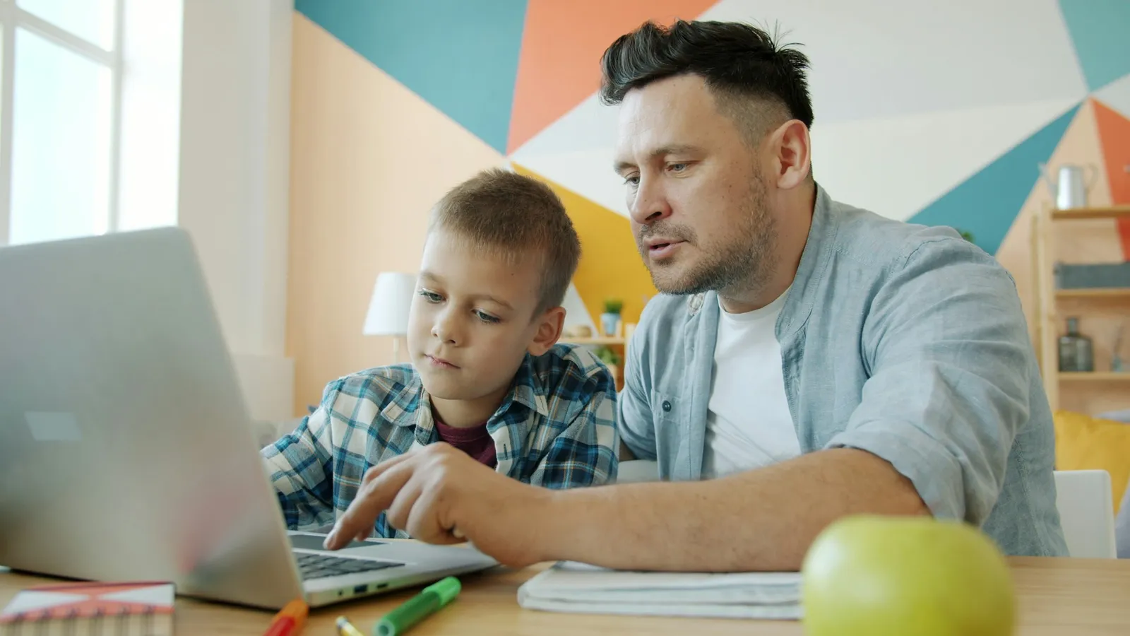 Father and son working through a problem together on a laptop