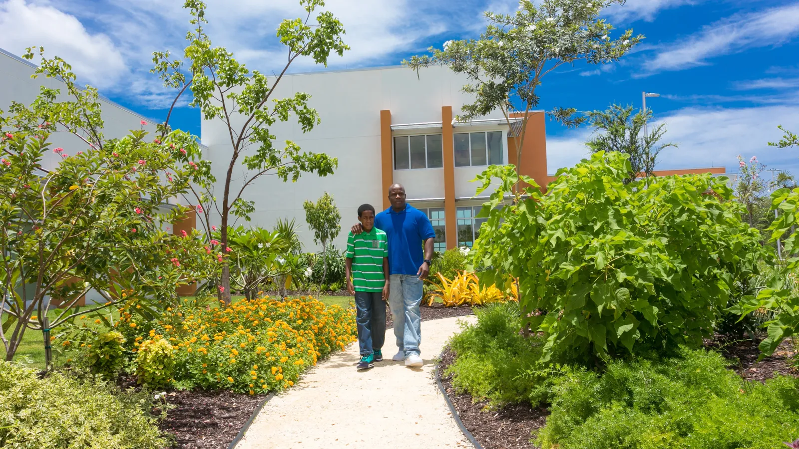 Father with his arm around his son, walking together along a garden path