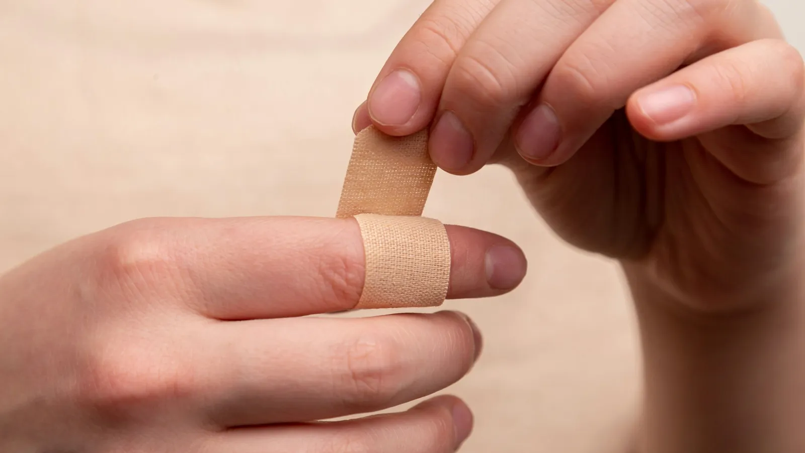Fingers placing a plaster over a small cut