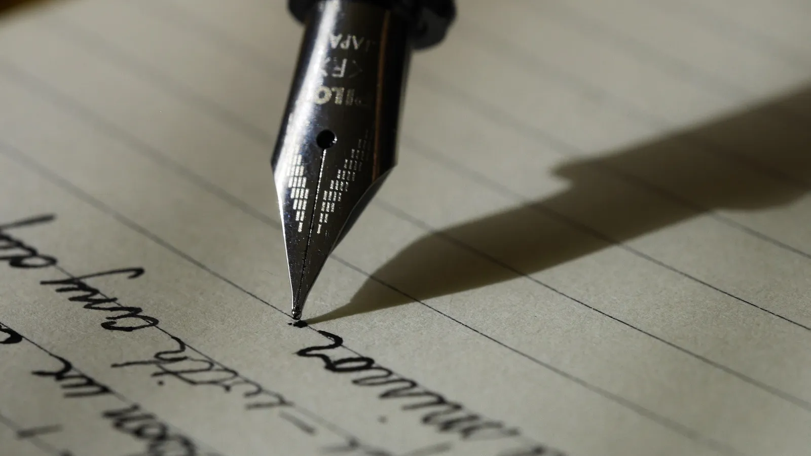 Fountain pen writing cursive handwriting on lined paper, close up