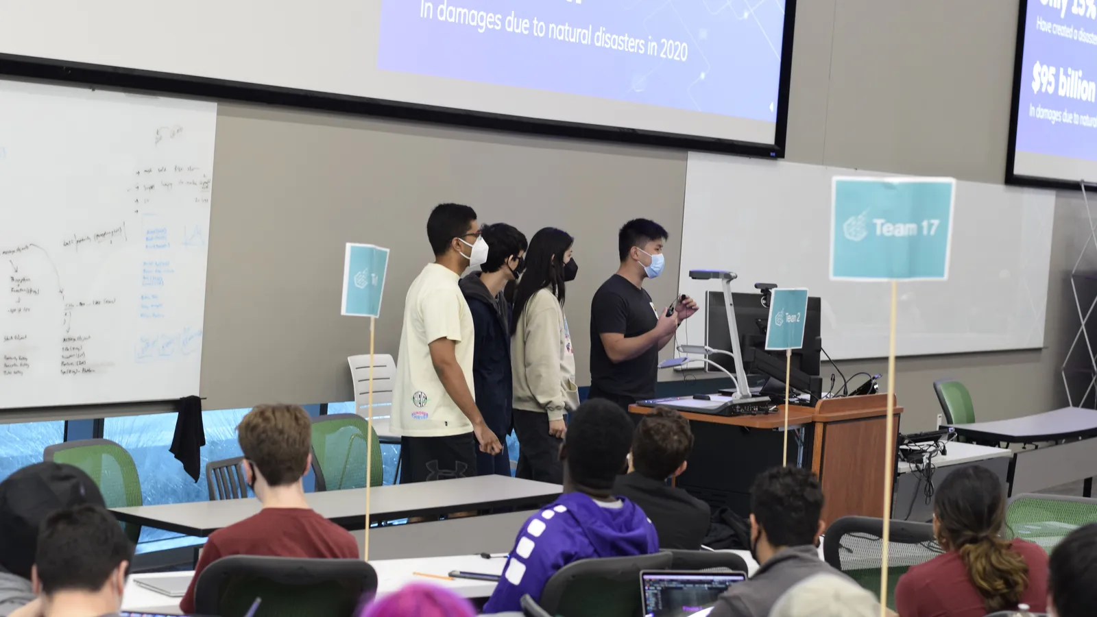 Four students presenting their team's hackathon project to a seated audience