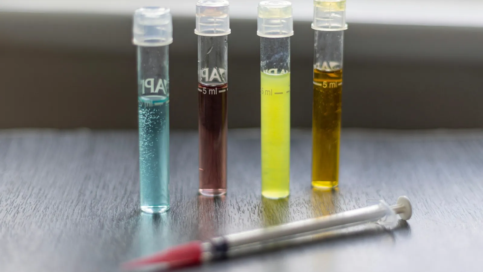 Four test tubes holding liquids of different colours