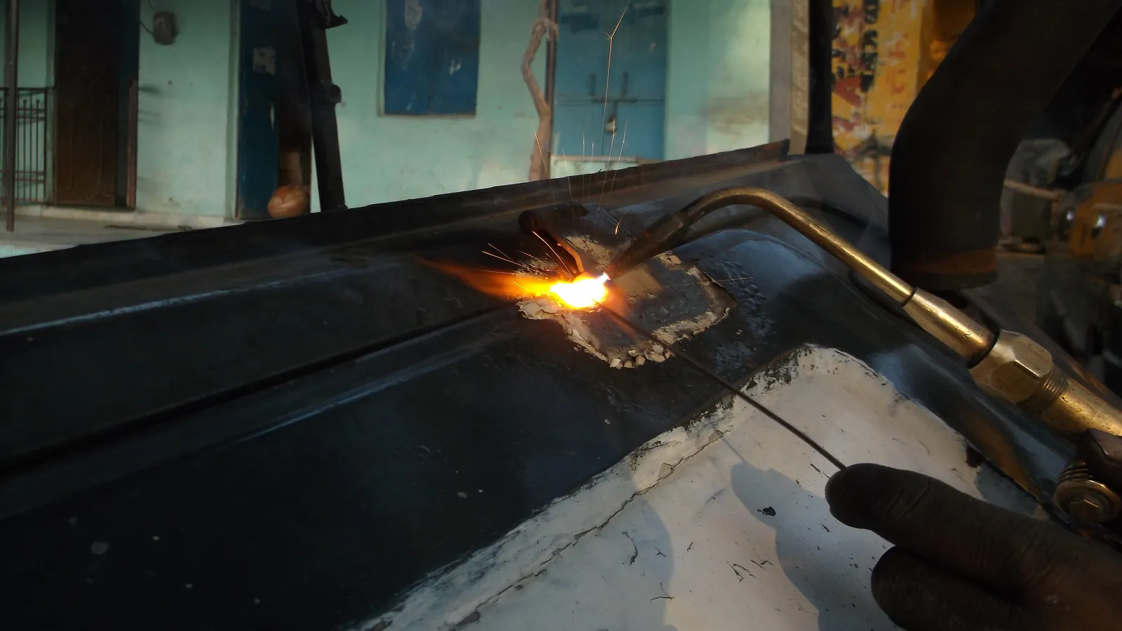 Gas welding torch and filler rod repairing a painted metal vehicle panel