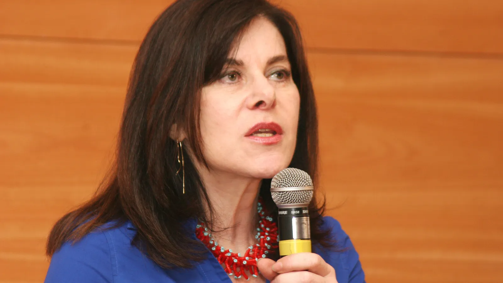 Geneticist Mayana Zatz in a blue top speaking into a microphone