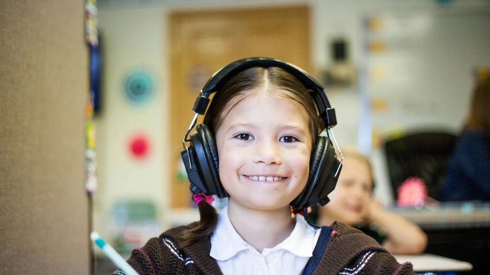 Girl wearing headphones smiling at the camera during a lesson