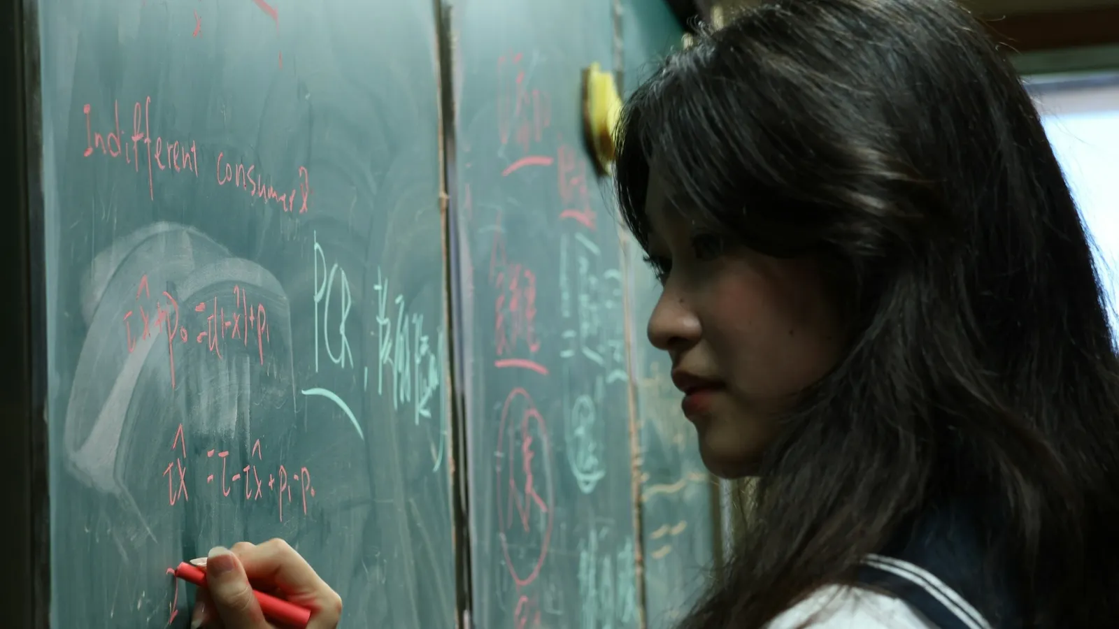 Girl working through a problem at a chalkboard