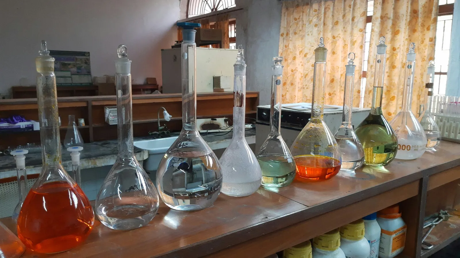 Glass flasks of coloured liquids on a laboratory bench