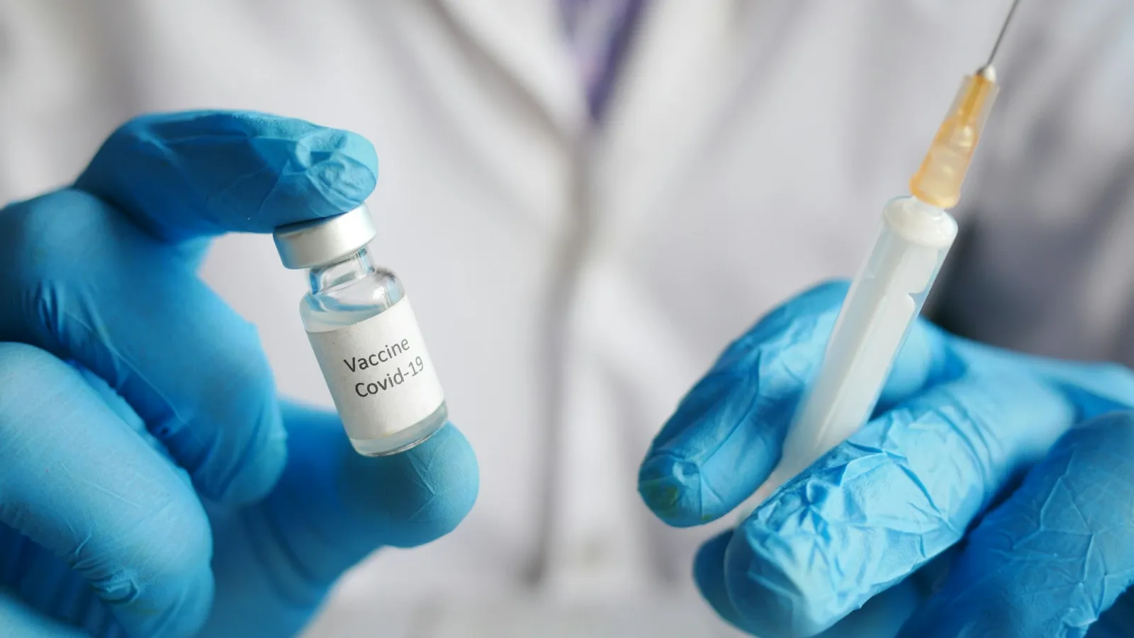 Gloved hands filling a syringe from a small vial