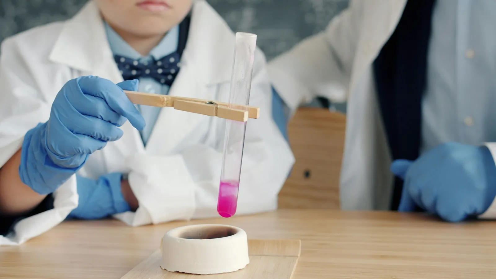 Gloved hands holding a test tube of pink liquid