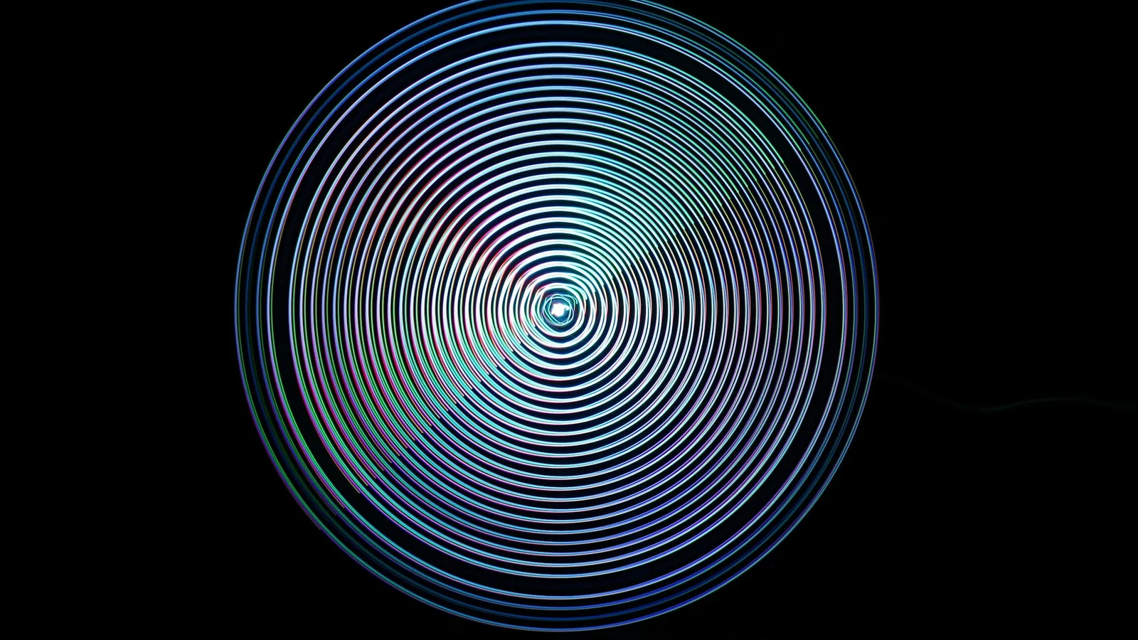 Glowing circles of light spinning on black