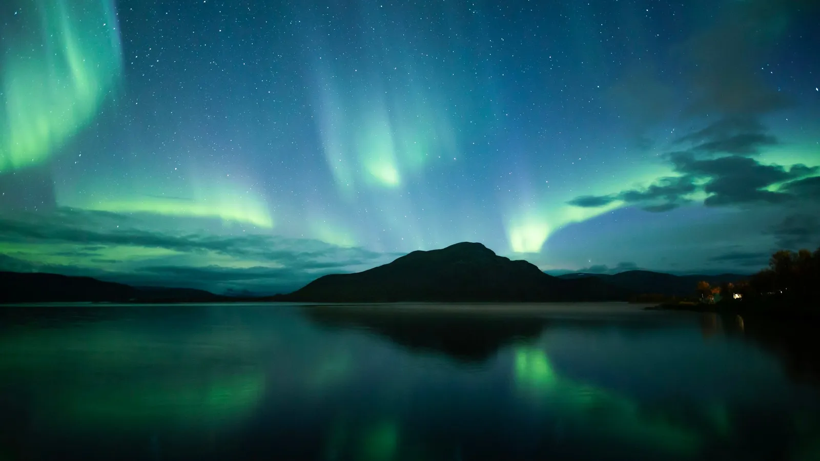 Green aurora above a lake at night
