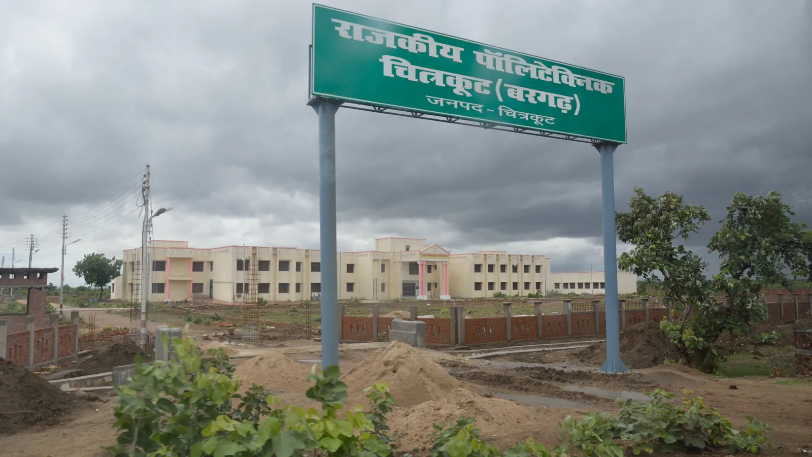 Green Hindi signboard for Government Polytechnic Chitrakoot in front of its campus building