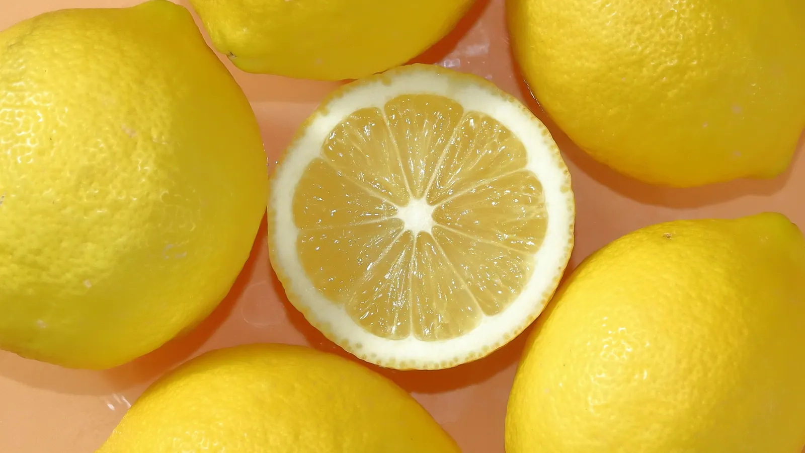 Halved and whole lemons on a peach background