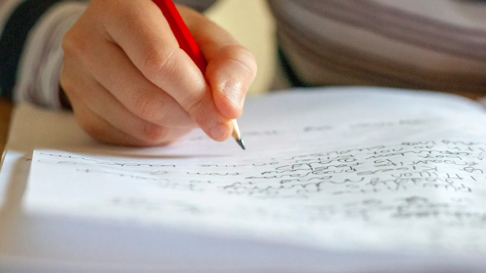 Hand writing neatly in a notebook with a red pen