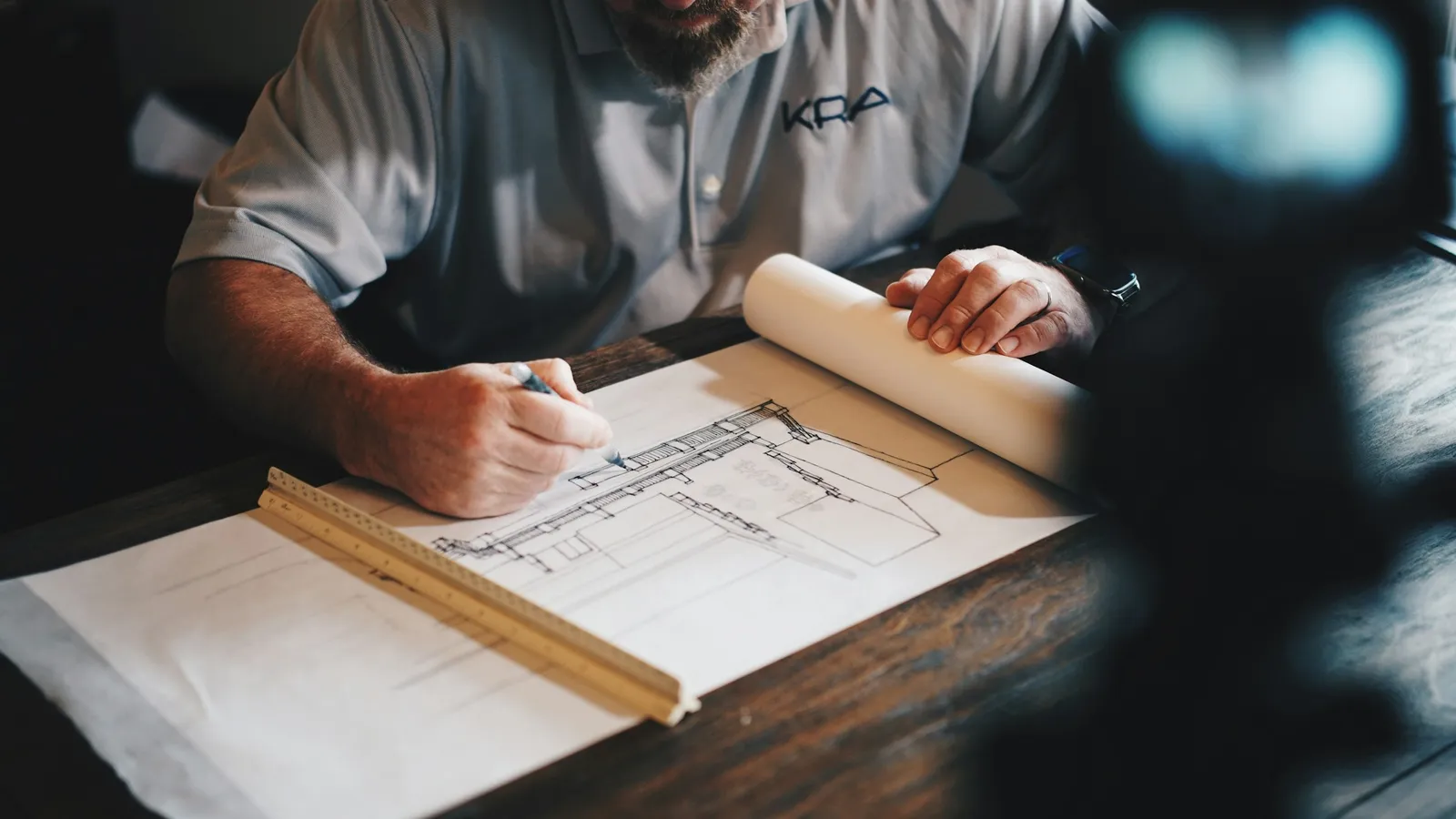 Hands drawing an architectural plan on a desk