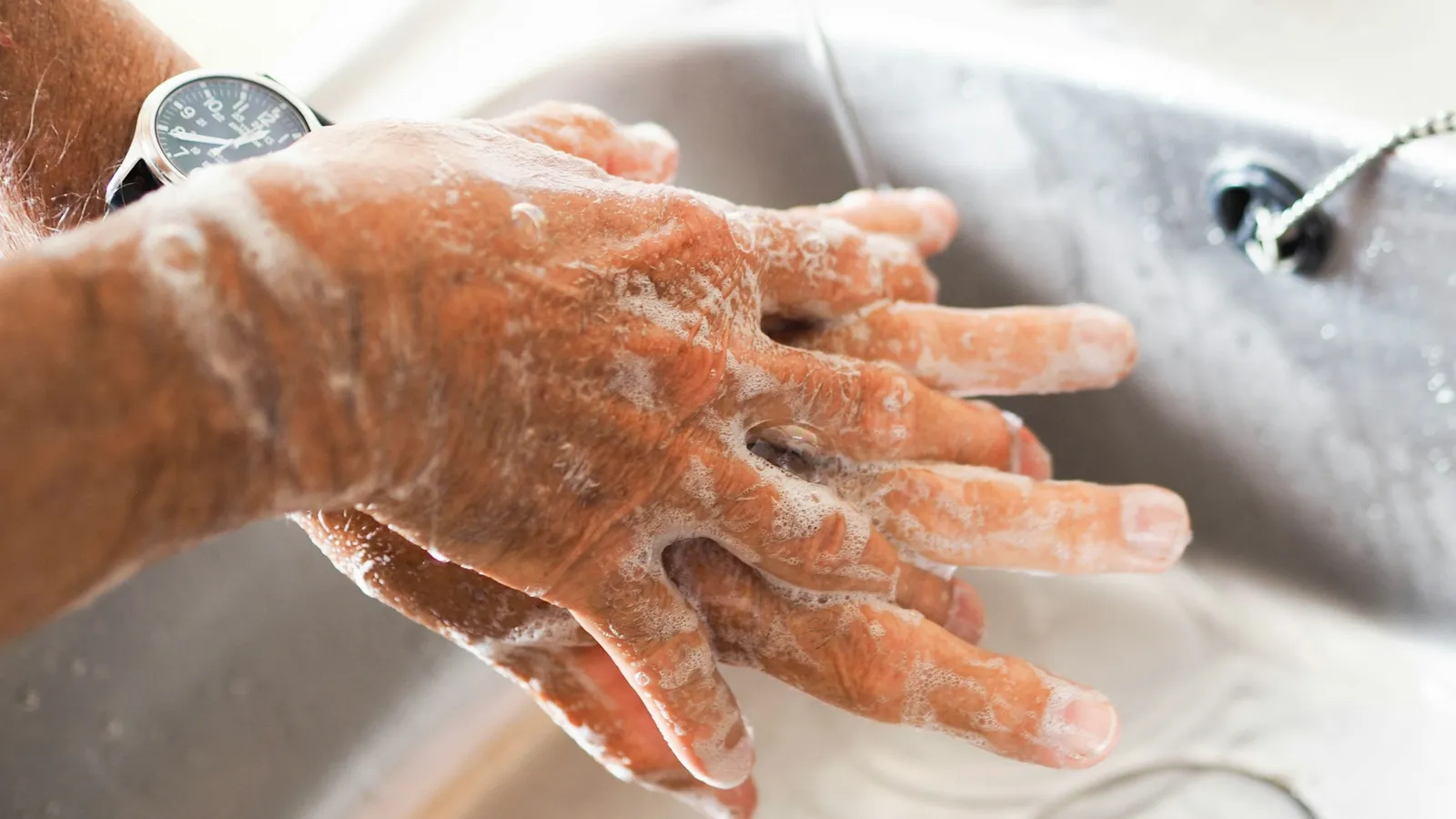 Hands lathered with soap being washed at a sink