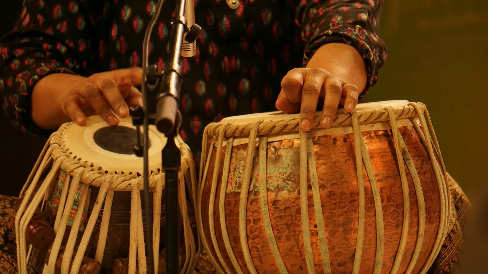 Hands playing a pair of tabla drums