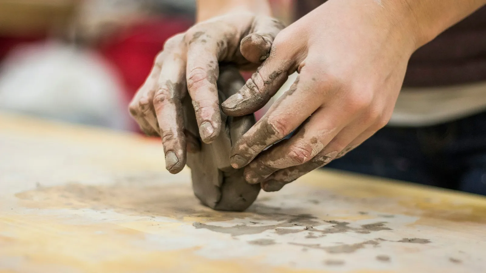 Hands pressing into a lump of soft clay