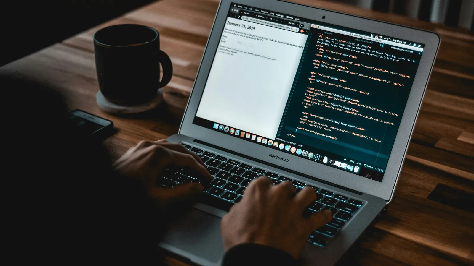 Hands typing on a laptop beside a coffee mug