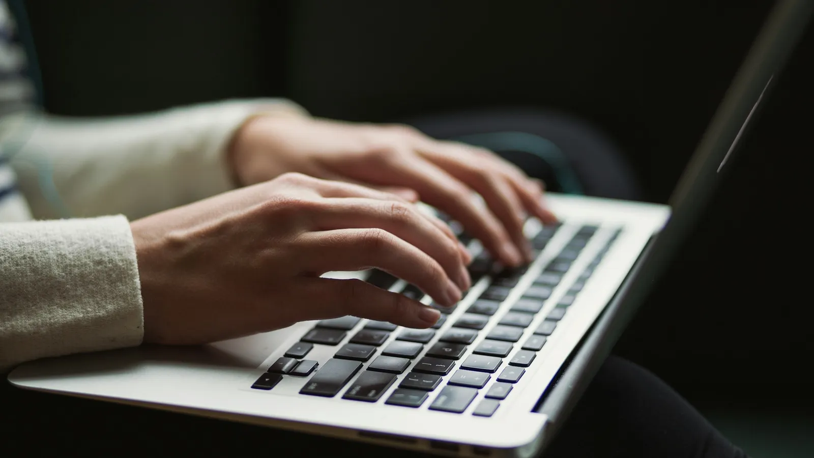 Hands typing on a laptop keyboard
