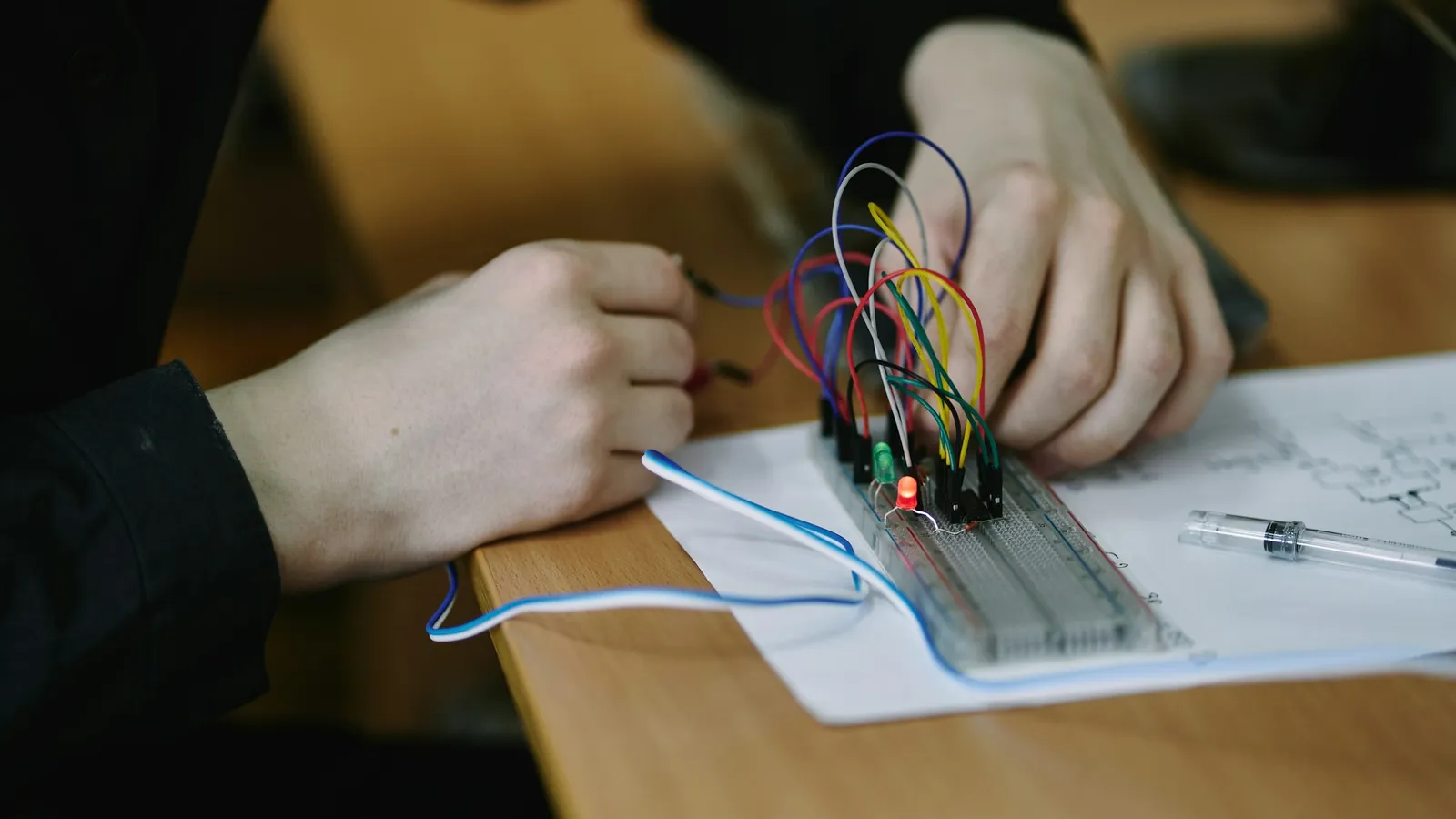 Hands wiring a small electronics project on a breadboard