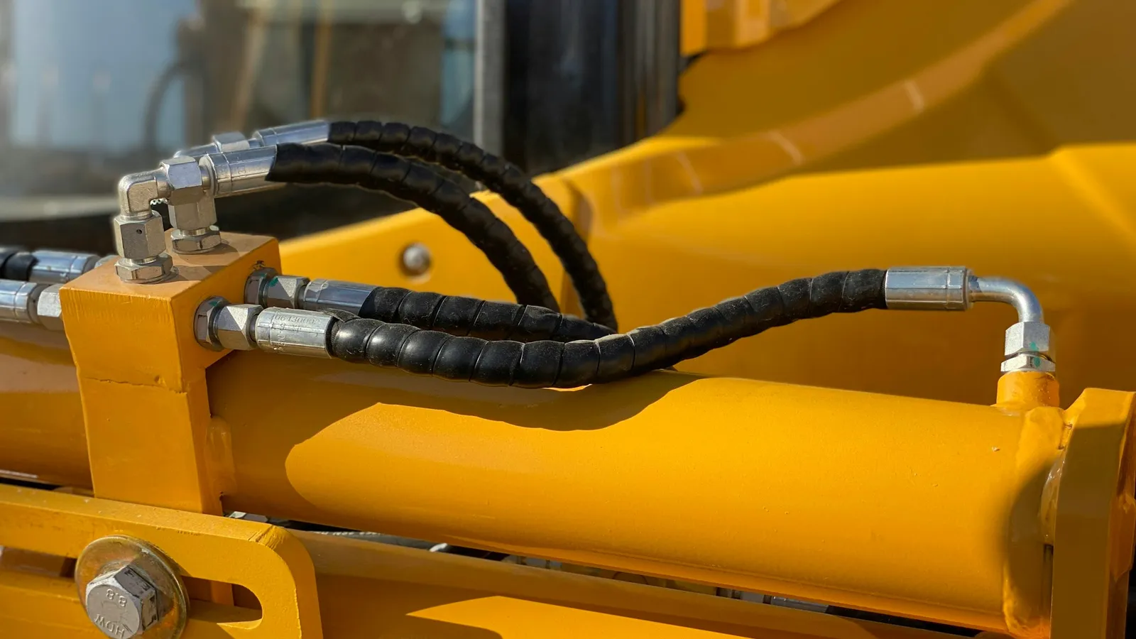 Hydraulic hoses on a yellow machine arm
