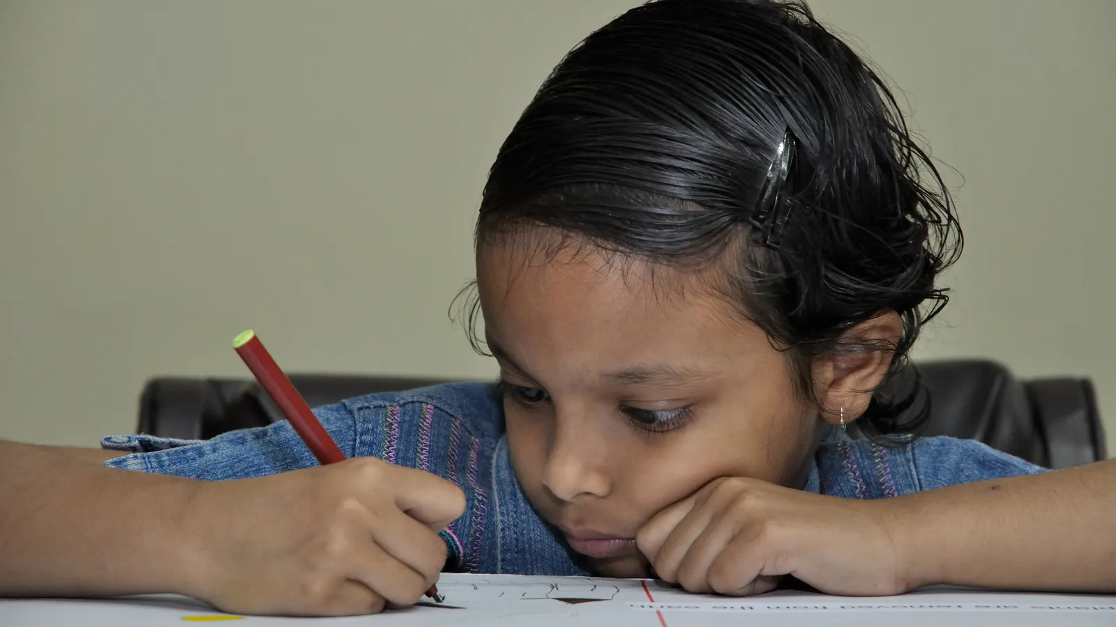 Indian school girl sitting at a desk looking down