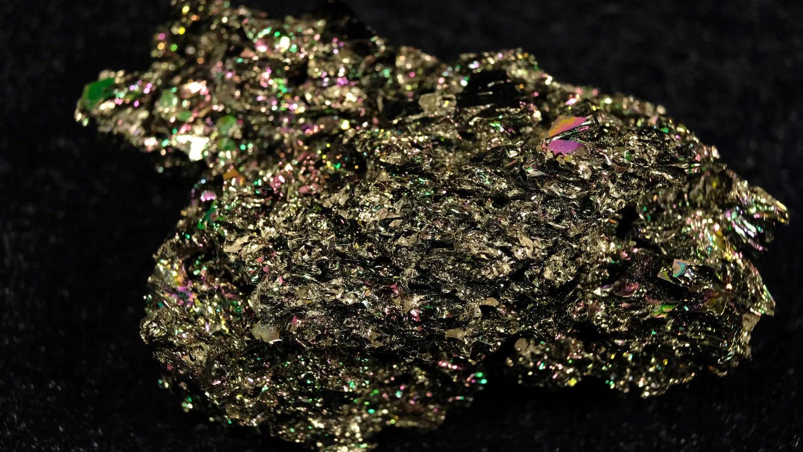 Large silicon carbide crystal with metallic green and purple glints on black cloth