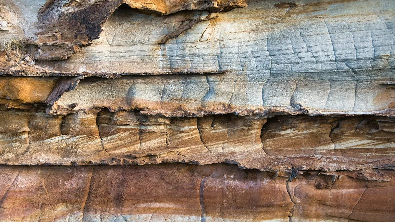 Layers of sedimentary rock in bands of grey, blue and orange