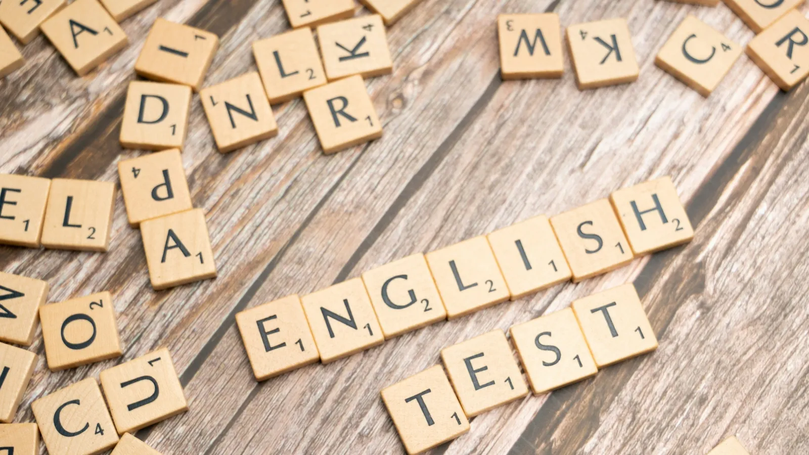Letter tiles spelling English test on a wooden surface